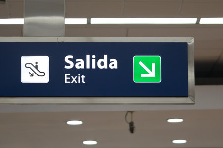 Blue exit signboard at an airport, written in spanish and english.の写真素材