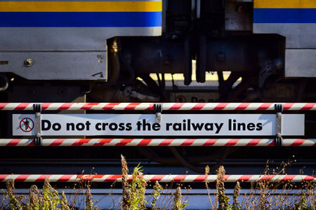 Warning sign at a train station in Italy, stating "Do not cross the railway lines" in English.の写真素材