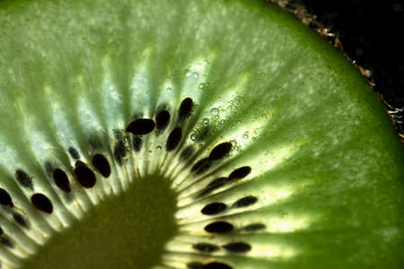Ultra close-up of kiwi slice. Macro of kiwi slice on black backgroundの写真素材