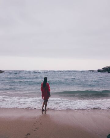 woman staring at sunset at tropical beachの写真素材