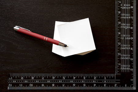 Note sticker, red pen and carpenter's square over black backgroundの写真素材