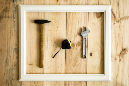 Old white frame Vintage frame with various tools on wooden background