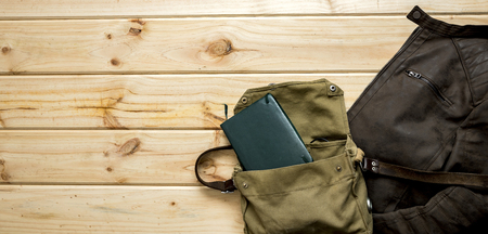 Panned jacket and notebook ready to travel over wooden background with space for textの写真素材
