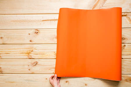 Hands unrolling colorful vinyl rolls on wooden background