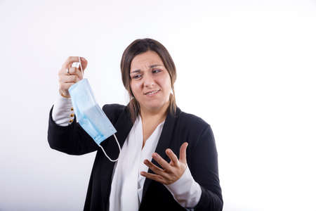 Young office worker girl shaking hand like Giorgio Tsoukalos saying "im not saying it was aliens but it was aliens" isolated on white background dressed in a suit holding a hygienic maskの写真素材