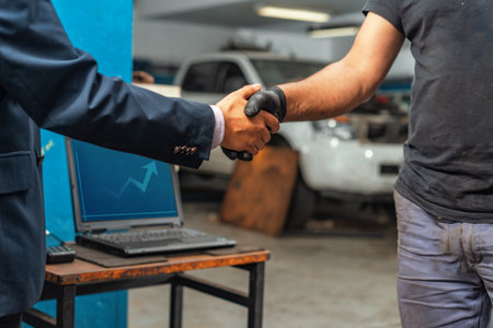 Close-up of auto mechanic worker and businessman client hands shaking hands during periodic car condition checkの写真素材