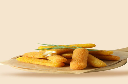 Fried cheese sticks in a wooden spoon on a beige backgroundの写真素材