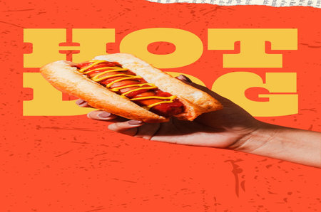 Hot dog with mustard and ketchup in a woman's hand on an orange backgroundの写真素材