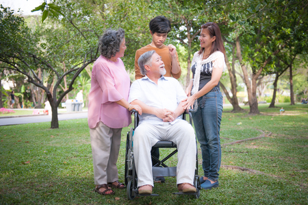 cheerful disabled grandfather in wheelchair welcoming his happy Familyの写真素材