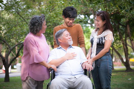 Cheerful disabled grandfather in wheelchair welcoming his happy Family. Family concept.の写真素材