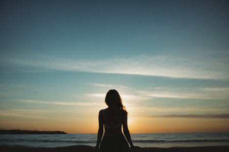 Silhouette of a beautiful young girl on the beach at sunsetの素材