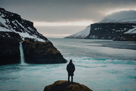 A man standing on the edge of a cliff and looking at a glacier. Icelandの素材