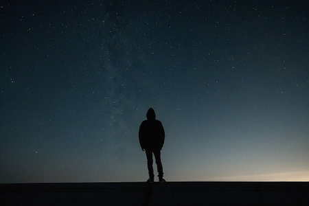 Silhouette of a man standing on the roof and looking at the milky wayの素材