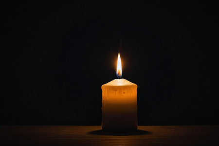 Burning candle on a wooden table, on a dark background.の素材