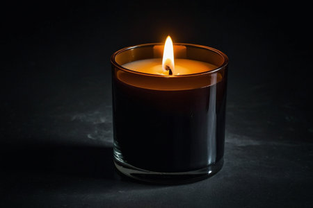 Burning candle in a glass on a dark background. Selective focus.の素材