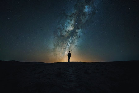 Silhouette of a man standing on top of a hill and looking at the milky wayの素材