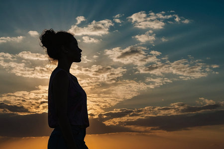 Silhouette of a young woman against the background of the sunsetの素材