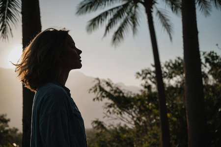 Silhouette of a young woman standing in the middle of the jungleの素材