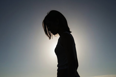 silhouette of a young woman on a background of the sunの素材