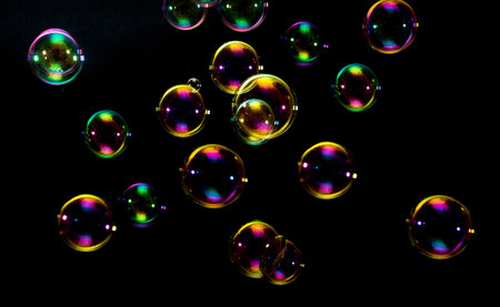 Colorful soap bubbles on black background, close-up view.