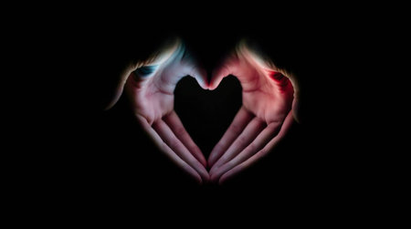 Hands in the form of a heart on a black background.の写真素材