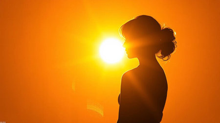 Silhouette of a beautiful young woman looking at the sun.の写真素材
