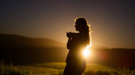 Silhouette of a beautiful young woman in the field at sunsetの写真素材