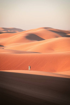 A man walking through the sand dunes in the desertの写真素材