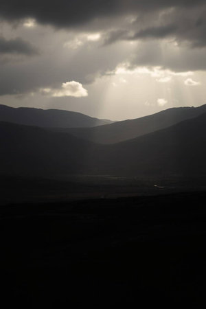 Dramatic sky with clouds and sunbeams over the mountainsの写真素材