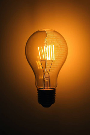 Incandescent lamp on a dark background with a glowing light bulbの写真素材