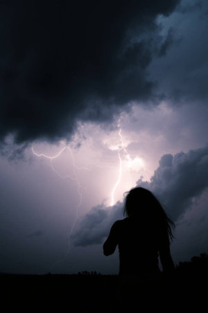 Silhouette of a woman in a stormy sky with lightningの写真素材