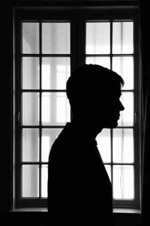 Silhouette of a man standing in front of a window.の写真素材
