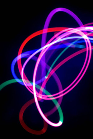Abstract background of colorful neon light curved lines on a black background.
