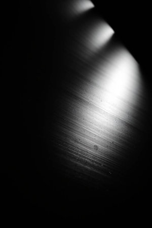 Brushed metal plate with some reflected light on it. Black and white photo.の写真素材