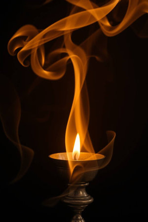 Burning candle in a candlestick on a black background.の写真素材