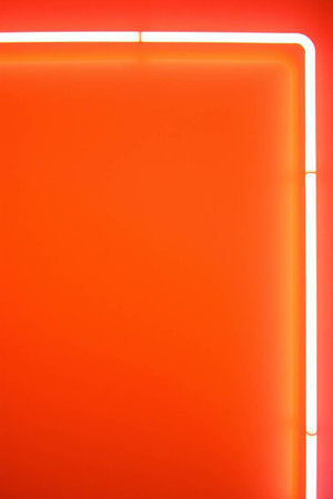 Neon sign on orange wall. Abstract background with empty space.の素材