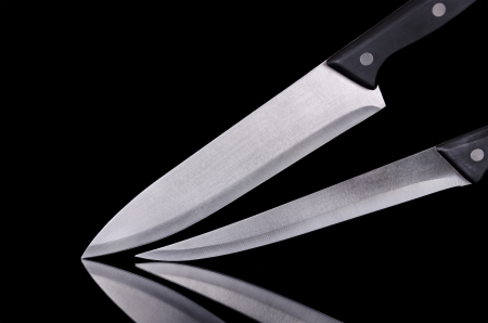 Close up view of two kitchen knives over black isolated backgroundの写真素材