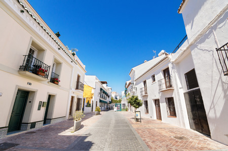 Typical street with white houses in the touristic village of Nerja, Malaga, Spain.の写真素材