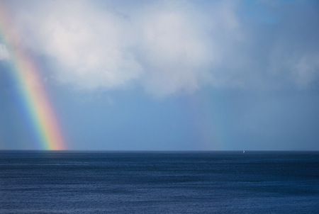 Beautiful rainbow and boat on the ocean horizonの写真素材