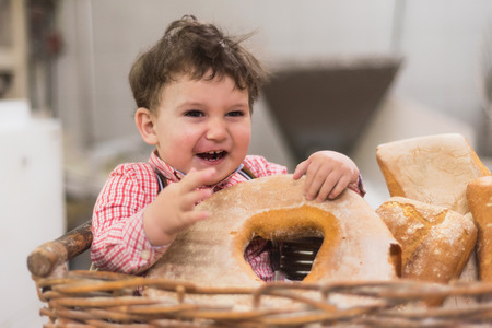 Portrait of a cute baby inside a basket with bread in the bakeryの写真素材
