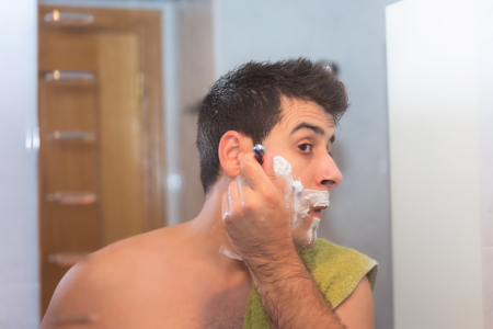 Handsome man shaving his beard in bathroomの写真素材