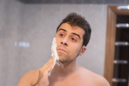 Handsome man shaving his beard in bathroomの写真素材