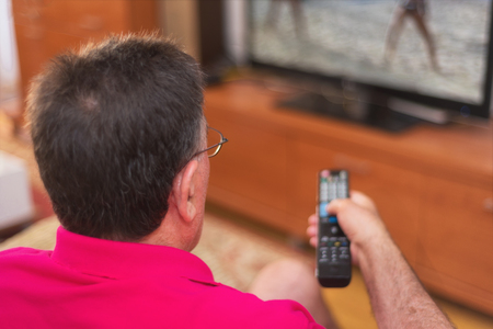 Back view of senior man watching tv holding remote controlの写真素材