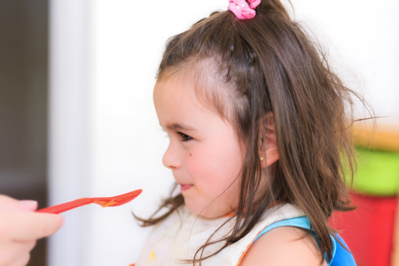Cute little girl eating pureeの写真素材