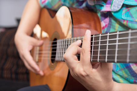 Bearded hipster man hand playing acoustic guitar. Close-up selective focus on hand.