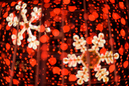 Red lights bokeh christmas background with golden snow flakes.