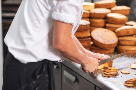 pastry chef cutting the sponge cake on layers. Cake production process.の写真素材