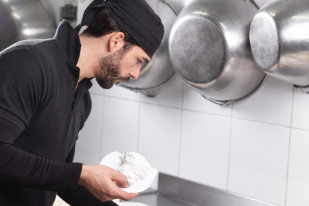 Handsome professional confectioner making a batch of delicious cake in the pastry shop.の写真素材
