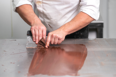 Professional confectioner making chocolate sweets at confectionery shop.の写真素材
