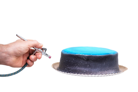 Hand of chef using airbrush for cake decorating on white isolated background.の写真素材